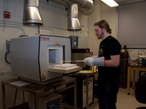 Undergraduate William Smith places materials into a furnace